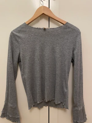 Långärmad tröja  - Säljer denna grå långärmad tröja med volang ärmar. Enkel och passar med vad som helst. Storlek M men passar S. Pris kan diskuteras. 