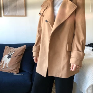 Kappa från Mango - Brun/beige kappa från Mango. Sparsamt använd, dock 2 knappar som är lite lösa. Storlek M. Finns att hämta i Lund/Malmö annars tillkommer frakt 