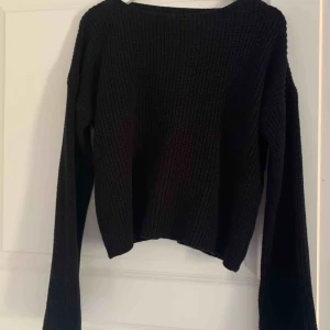  - Svart stickad tröja från NA-KD med utsvängda armar. Det finns ett litet hål på baksidan av tröjan men syns knappt.
