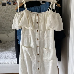 Gullig vit klänning - Vit offshoulder klänning med bruna knappar. Använd en gång (skolavslutning) och är i storlek 36. Säljer pga att den blivit för liten. 