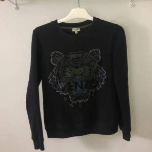 Kenzo tröja - Säljer en äkta kenzotröja, använd max 4 ggr! Storlek S dam, svart med silvriga, mörkt grön, gråa o blåa detaljer. Kenzo texten är i svart ”lack”liknande material. Köpt på NK i Göteborg för 2 år sedan för 2300kr! Pris kan diskuteras vid snabb affär💝💝