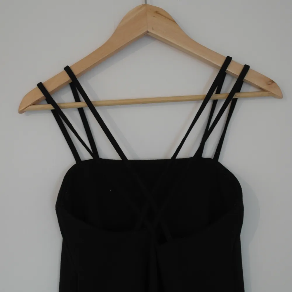 Stilren svart klänning med dubbla axelband som korsas i ryggen. Klänningar.