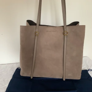 Ralph Lauren Lennox Tote L/ New - Väska från Ralph Lauren, modell Lennox Tote L i äkta mocka. Väskan är helt ny! Rymmer en laptop och är uppdelad i tre fack med ett mittenfack med magnetlås. Dustbag ingår. Mått: 37,0 x 33,0 x 12,5 cm. Nypris: 2 850 kronor. Skriv för fler bilder! :) 