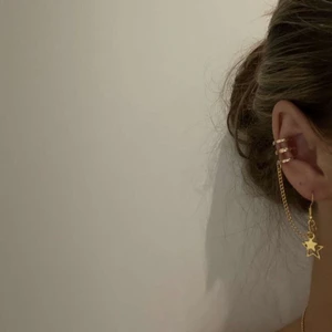 Earcuff, smycken  - I05. Jättefin earcuff, tillhörande örhänge följer självklart med. I guld med stjärnor. Glöm inte att 10% av visten får oavkortat till organisationen kvinna till kvinna. 