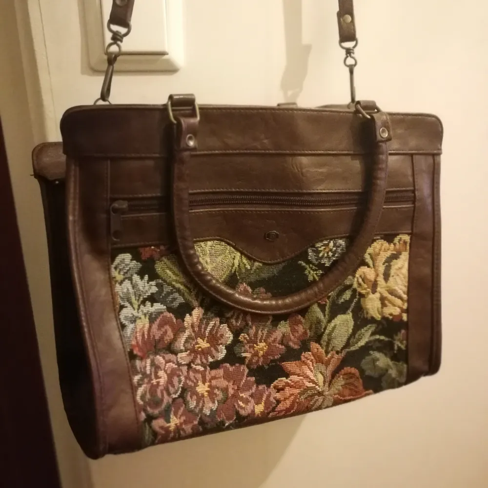 En stor vintage handväska med blommigt tyg. Vet ej om de är äkta skin. Den är rymlig med 3 fack. . Väskor.