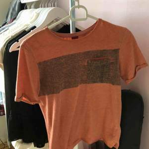 Orange tröja med ett grå/svart sträck över bröstet. Klippt av den nertill (se bild två) därav priset. Annars väldigt skön och luftig.