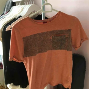  - Orange tröja med ett grå/svart sträck över bröstet. Klippt av den nertill (se bild två) därav priset. Annars väldigt skön och luftig.