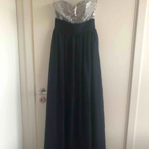  - Mörkblå klänning med hjärtformad urringning och korsad rygg.. paljetter på både fram och baksida..  Helt ny med etiketten kvar ..