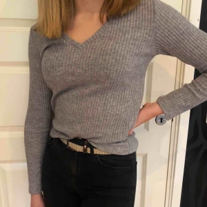  - En enkel grå V-ringad tröja som passar till det mesta. Den är väldigt stretchig så den passar storlekarna S-L Använt 1-2 gånger och är i gott skick 