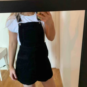  - Svart hängsleklänning i manchestermaterial ursprungligen från H&M. Använd ett fåtal gånger. 