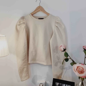  - Tröja som ALDRIG ÄR ANVÄND! Beige tröja med ”puff armar”. Kommer tyvärr inte till användning. 