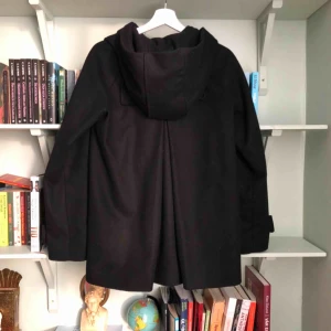  - Klockad, kortare modell med gömda knappar och luva som dessvärre är lite för liten för mig. MYCKET sparsamt använd. Jag har vanligtvis 36/38 och denna är precis  för kort i ärmarna och lite för trång över ryggen.   Material: 80 % ull 20 % polyester  