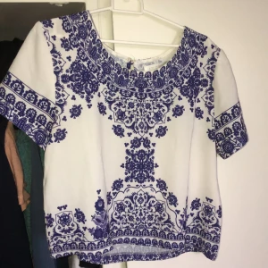 Vit blus med blå detaljer - Så fin blus men tyvärr för liten för mig! Slutar vid midjelängd. Ej genomskinlig, passar till det allt💕 frakt tillkommer!! Skriv för fler bilder🥰