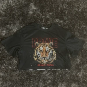 Fin kort T-shirt med tiger motiv  - Säljer en T-shirt med, ganska kort så magtröja liknande. Säljer endast då jag inte tycker den passar mig. Pris 50kr, kan skickas om köparen står för frakt (30kr).) storlek S, men passar nog någon med M också. 