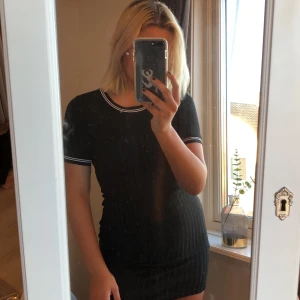 Svart ribbad klänning  - Svart ribbad klänning från H&M med vita detaljer. Använd ett fåtal gånger, nästintill nyskick, frakt 30kr sitter bra på mig som är 169cm lång