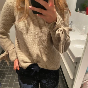 Stickad tröja ifrån Gina i storlek m - En stickad tröja som knyts i ärmarna. Den är i storlek m och säljs för 100kr. Som man ser på bilden är den lite nopprig på vissa ställen.
