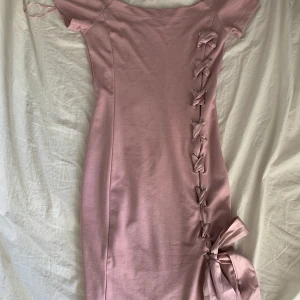 Tajt rosa klänning  - Denna gammelrosa klänning sitter tajt och har snörning tills slutet då de kommer en rosett (går och göra om) silkestråden går som kors och sitter tyg under så man kan ej se något där en simpel men fin klänning, frakten tar vi senare isåfall💗💗💗