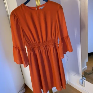 Fin orange klänning - Fin orange klänning från hm i storlek 38. Har lite krus på ärmarna och i midjan, sitter jätte fint, ganska kort på mig (180cm) men är nog närmare knänen på nån som är lite kortare