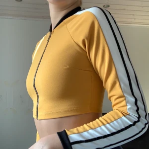 Gul topp - Gul topp med vita och svarta detaljer på ärmarna. Mycket bra skick. Stl xs. 