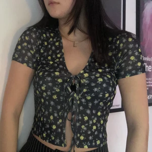 Topp med knytning - Blommig söt topp med knytning framtill. Passar att ha (som jag har) utan något under men också jätte snygg att slänga över en långärmad eller liknande! Aldrig använd. Köpare står för frakt.