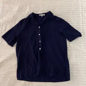 Marinblå skjorta med korta ärmar i strl L. Bröstfickor med broderingar och silvriga knappar finns. 