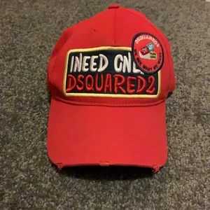 DSQUARED 2 Keps, Röd. - Size: Adjustable. Kvitto finns ej. Condition: 8/10. Inte 100% säker på äktheten då jag köpte den här på plick utan kvitto men säljaren har fått väldigt bra feedback. 