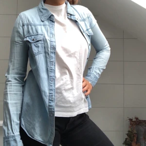 SKJORTA - En jeansskjorta från märket ONLY. Ett liiitet hål under vänstra armhålan men inget som syns. Kan knäppas upp på mindre storlekar men passar bra som på bilden för storleken M.