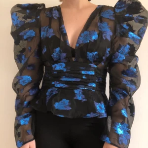 Party-topp  - Festlig topp i genomskinligt material. Blå glittriga detaljer. Storlek M.