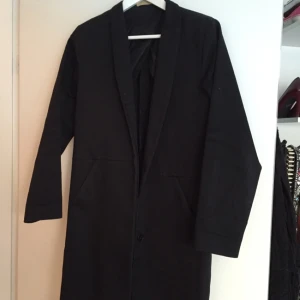  - Svart kappa från Whyred. Rak i passformen och får ungefär till knäna på någon som är 165 cm 