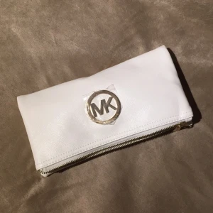  - Vit Michael Kors handväska med gulddetaljer. Köpt utomlands så kan ej garantera äkthet. Innerfack med dragkedja samt fack för mobil och plånbok. Medföljer 2 st remmar, en lång samt en kort. Hör av er för mer info/bilder 