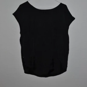  - Svart blus med paljetter i ryggen. Mycket snygg, längre på ryggen och kortare framtill. Från just female