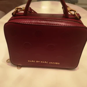  - Vinröd väska i läder med kort handtag el långt över axeln går att variera knappt använd köpt i new York 