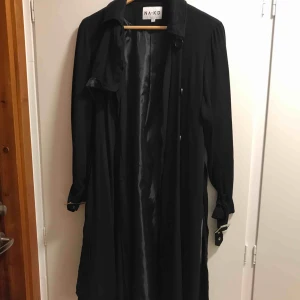  - Oanvänd svart trenchcoat från na-kd. Snygga spännen i ärmarna och band i midjan. Kan skicka och då tillkommer frakt. 