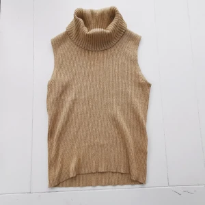  - Super snygg, stickad, ärmlös polo topp. Beige med inslag av guldglittrig tråd. Perfekt skick. 70% bomull resten Polyester, sticks inte och har inte blivit det minsta noppig, känns som ny  . Köparen står för frakten 🌠