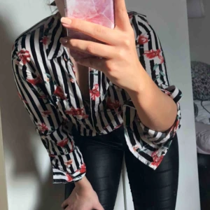  - Svart och vit randig skjorta med röda blommor. Jättefin och i bra skick. 