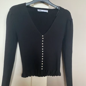 Zara tröja - Jätte fin zara tröja med vita pärlor, den går att använda som tröja men även som kofta då de vita pärlorna går att knäppa upp så de blir en kofta, den har små volang detaljer längst ner på armarna och längst ner på tröjan! Använd typ 2 ggr så jätte fint skick, passar perfekt till fin middagar eller fest!💕💕 kund står för frakt 63kr