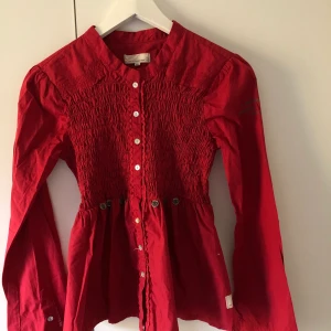 Oddmolly blus - Oddmolly blus i en magisk röd färg, fin i höst med ett par svarta jeans! Använd fåtal gånger, skicket är bra men dessvärre en knapp som åkt av i mitten på tröjan. Därav 50kr avdrag. Blusen är mycket festlig med detaljerna som ni ser på bilden. Prisvärd!