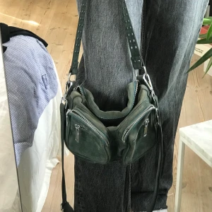 Grön noella väska - Väska i en jättefin grön färg från Noella. Har två axelband, det långa kan tas av. Har många fack och rymmer mycket💕 säljer för 250kr + frakt (köparen står för fraktkostnad)