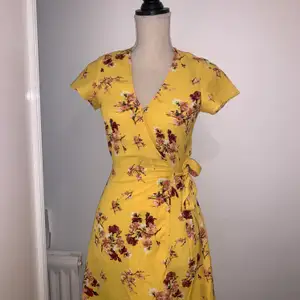 Kort gul klänning med blommor, knytning på sidan. Köpt för ett år sedan på H&M. Endast använd en gång. 100 kronor + frakt🛍