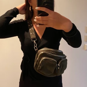 Militärgrön väska - Militärgrön väska från Gina Tricot. Nyskick endast använd ett fåtal gånger. Tillkommer även ett oanvänt lite längre band som går att byta mot det korta om man vill använda den som en crossbody (i samma färg och material). Många 2 stora fack med ett mindre inuti samt två mindre fack på utsidan, väldigt användbar.  Kampanj: KÖP 3 BETALA FÖR 2