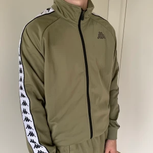 Grön KAPPA tracksuit jacka  - Säljer denna gröna KAPPA tracksuit jacka i storlek M. Fint skick, använd fåtal gånger. Spårbar frakt tillkommer på 63 kr. Kan köpas som ett set tillsammans med byxorna 