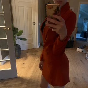 Kavajklänning / kavaj - Kavaj eller kavajklänning i färgen rödorange.snyggr figursydd. Använd en gång, men har fått ett par öglor som syns om man granskar noga. Se bild. Storlek 32. 