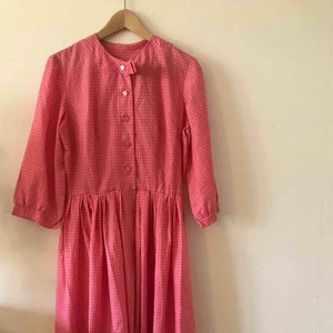  - Mycket vacker klänning i 50-tals stil i en varm, rosa färg. Stor vidd på kjol. Knappar framtill.  Storlek: Passar 38/40. Skick: Nästan oanvänd.  Kan skicka mot frakt i PostNords blå färdigfrankerade kuvert.  