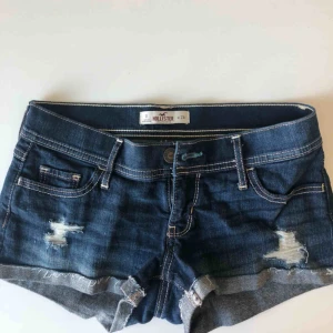  - Säljer mörkblåa Hollister shorts med slitningar.  Storlek 24W men passar även 25! Säljer pga de är försmå för mig och använder inte dem längre! 