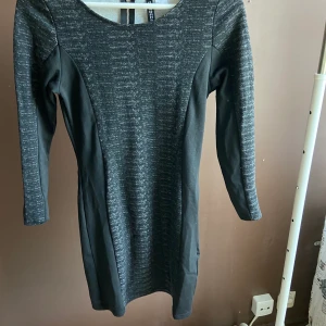 Långärmad klänning - En svart/grå tight klänning från H&M. Använd ca 2 gånger. Stretchig. Frakt tillkommer