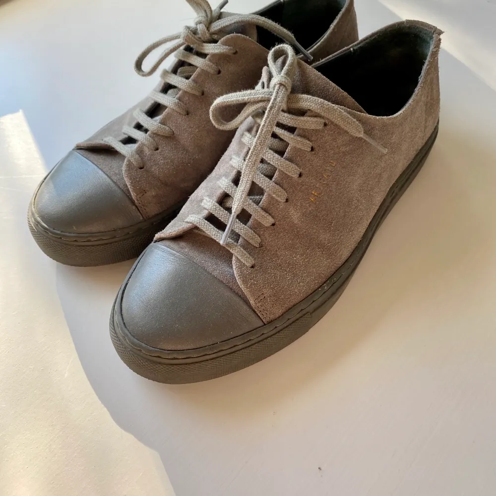 Hej! Jag säljer ett par axel arigato skor i färgen grå. Riktigt snygga och i bra skick. Finns en liten skråma på ena skon (se bild) annars jättefina och fräscha. . Skor.
