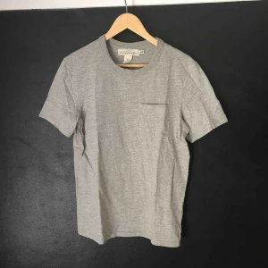 - Grå H&M t-shirt med ficka på framsidan. Nyskick. 