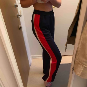  - Mörkblå byxor med rött och rosa streck. Använda 1 gång.