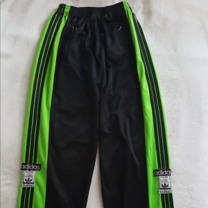  - Vintage adidas byxor i svart och neongrönt. De är i fint skick förutom att tryckknapparna har varit svarta men flagnat av (se bild 2). De är storlek M men då de är rätt små men väldigt stretchiga skulle jag säga att de nog passar storlek från XS till L. För mer info eller bilder så är det bara att höra av sig. Kan skickas om köparen står för frakten, som då blir 72kr.
