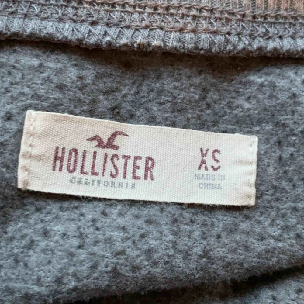 Hollister tröja som är grå med vit text där det stå hollister. Även ett litet märke i slutet av tröjan. Hoodies.